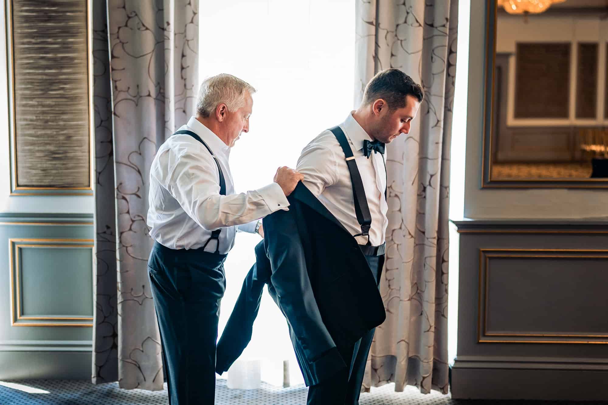 grooms father helping his son to dress up