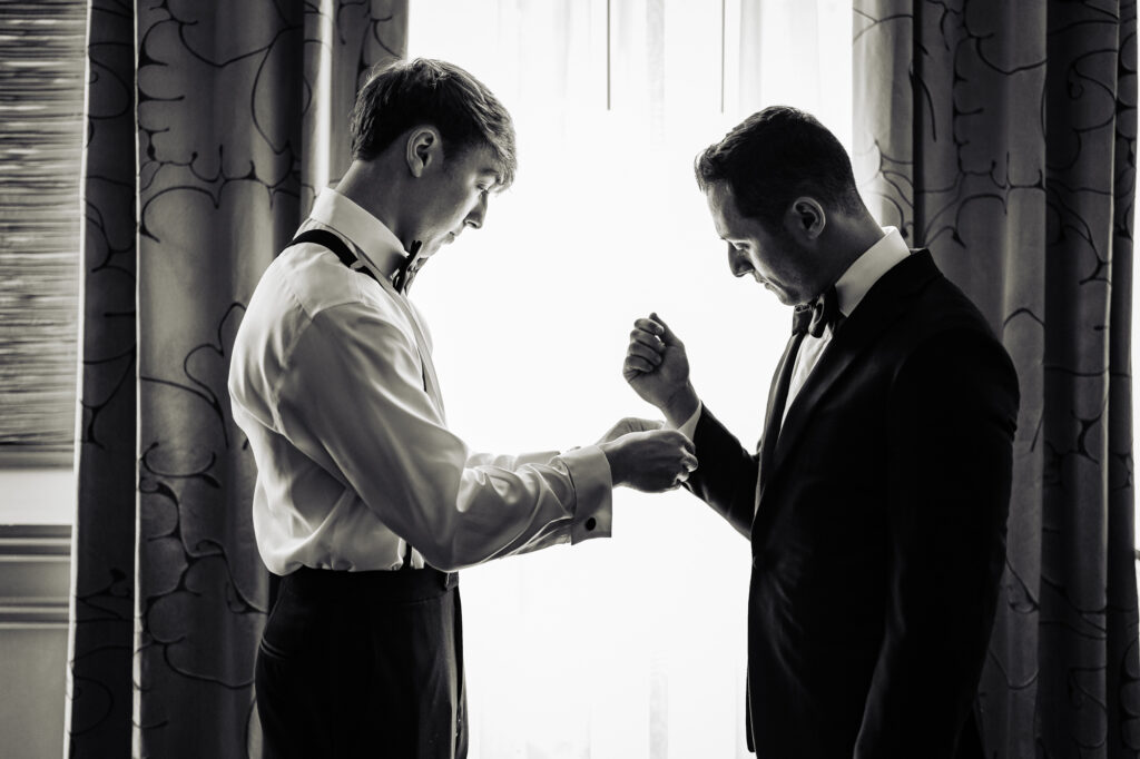 black and white shot of the groom getting ready with the help of his bestman