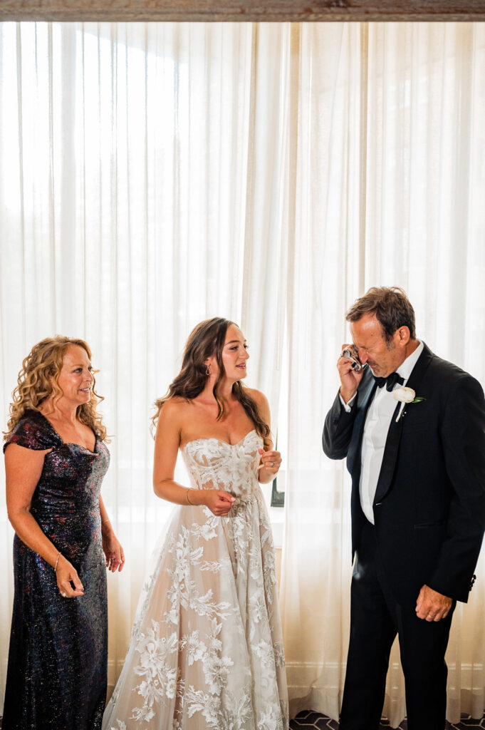 bride and his parents with the father getting teary-eyed upon seeing her daughter