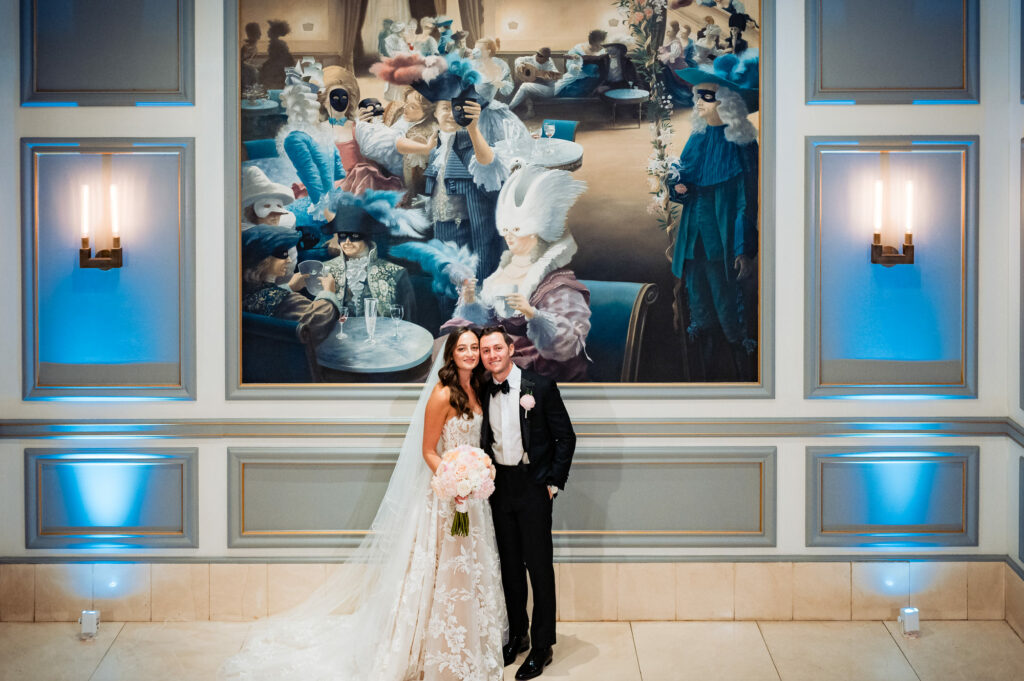 bride and groom posing in front of a huge painting at the rittenhouse hotel