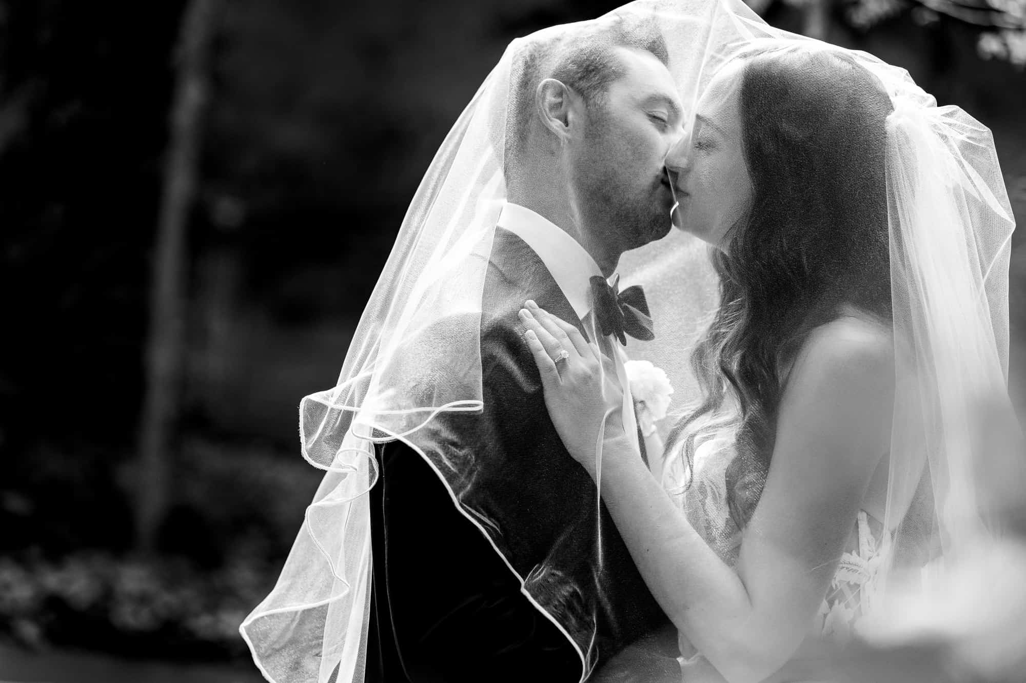 black and white shot of the newlywed's first kiss after their wedding ceremony