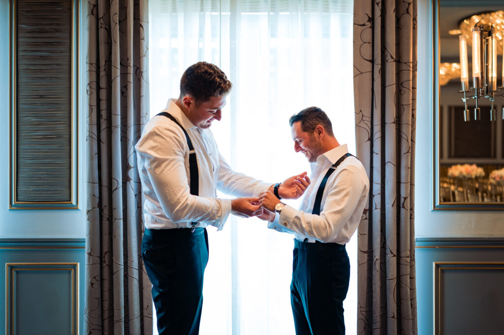 groom getting ready with the help of his bestman in their rittenhouse hotel executive suit