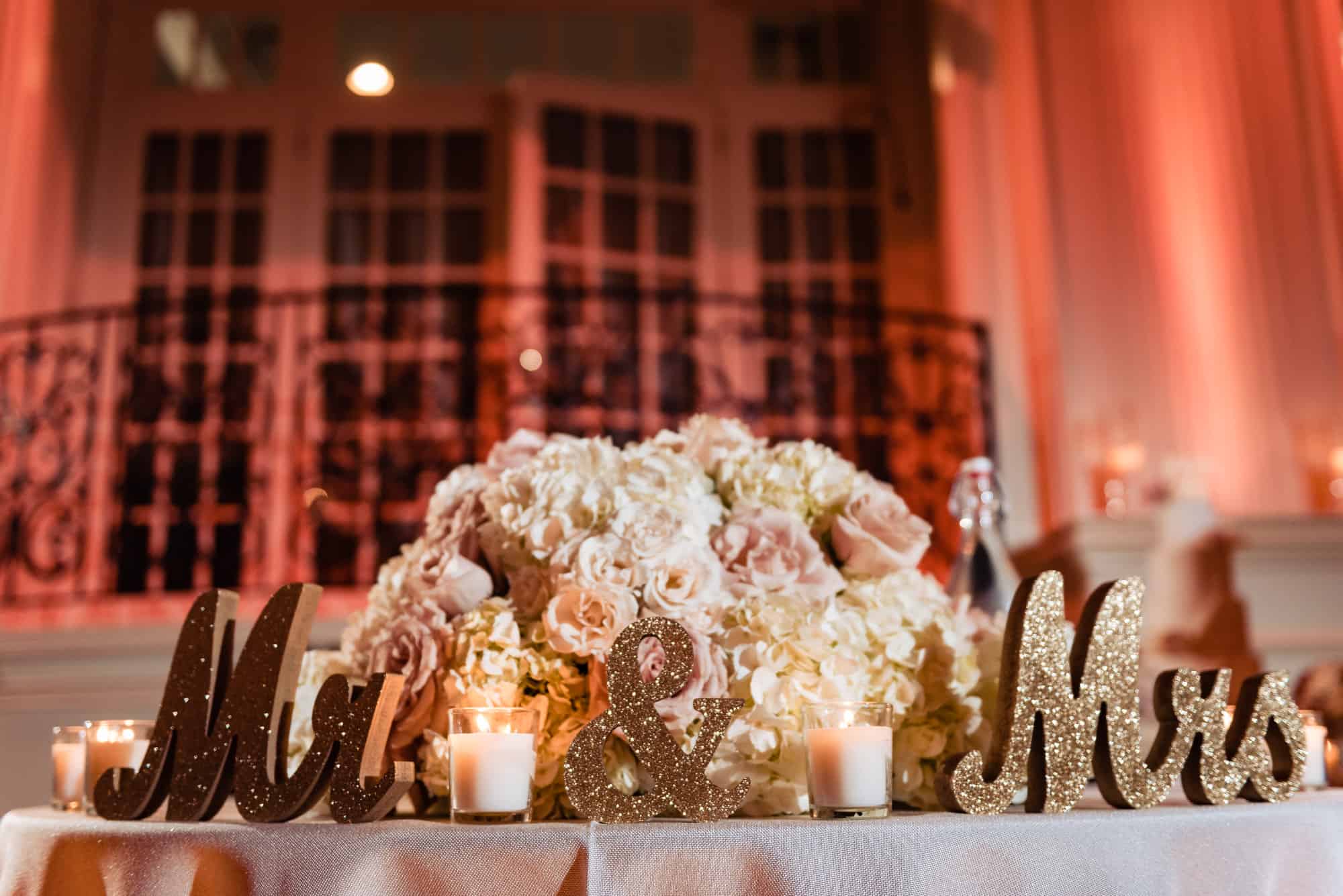 the presidential table adorned with pastel colored flowers and gold signage of mister and missus