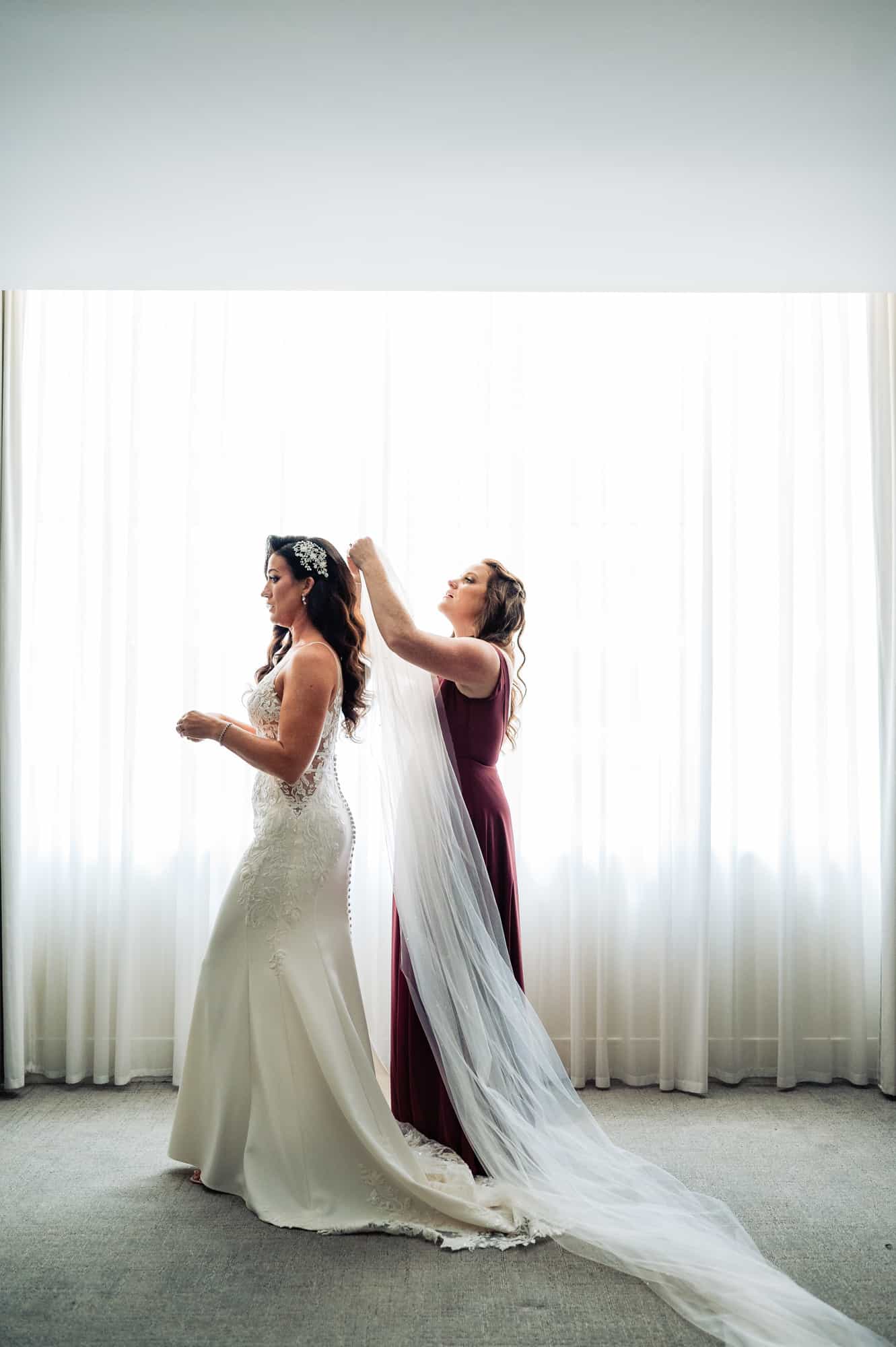 bride wears her veil with the help of her maid of honor