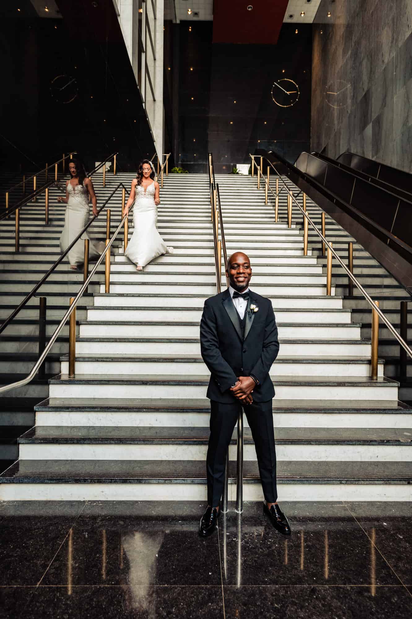 bride walks down the stairs while his groom is waiting down below