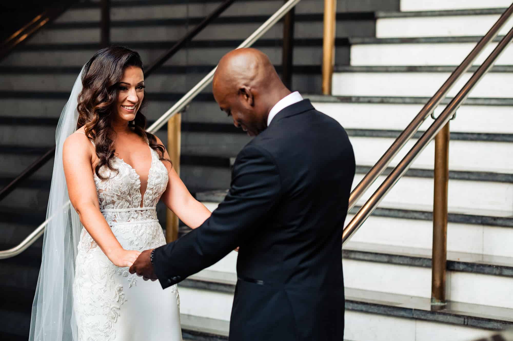 groom is looks at his bride's gown