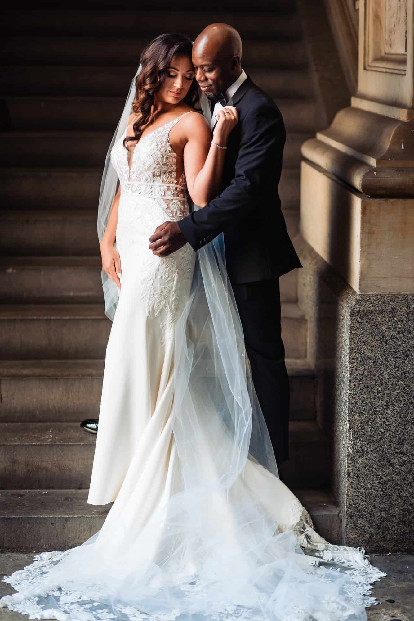 couple takes a candid pose beside a concrete post