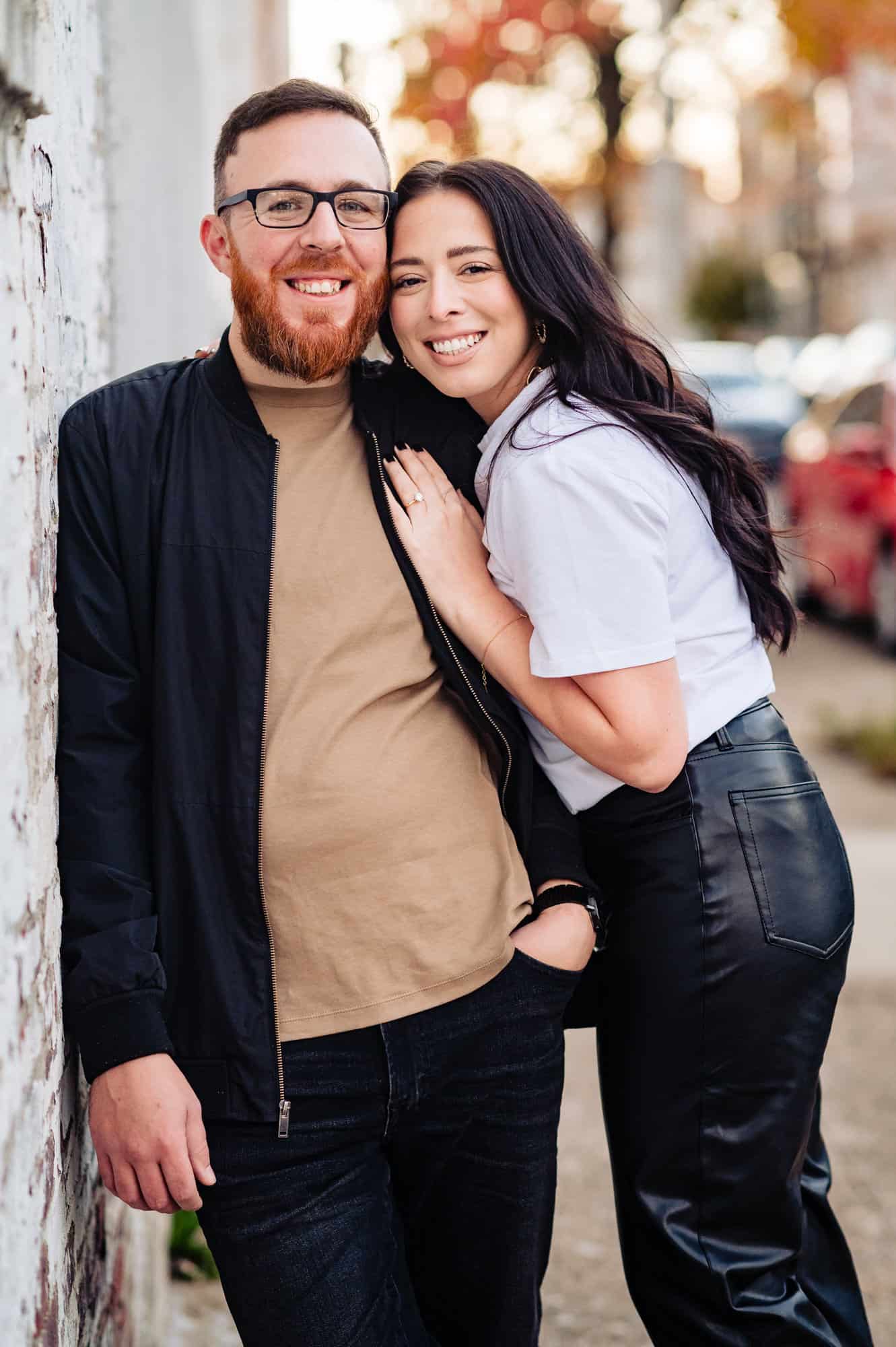 An engagement shoot on the street in South Philly shows the couple smiling for the camera