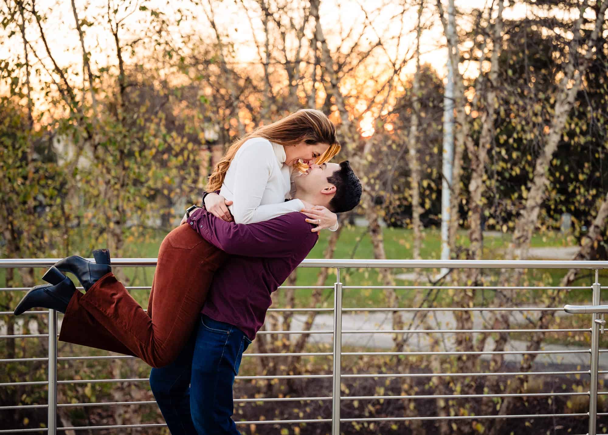 man carries his fiancé outside a park