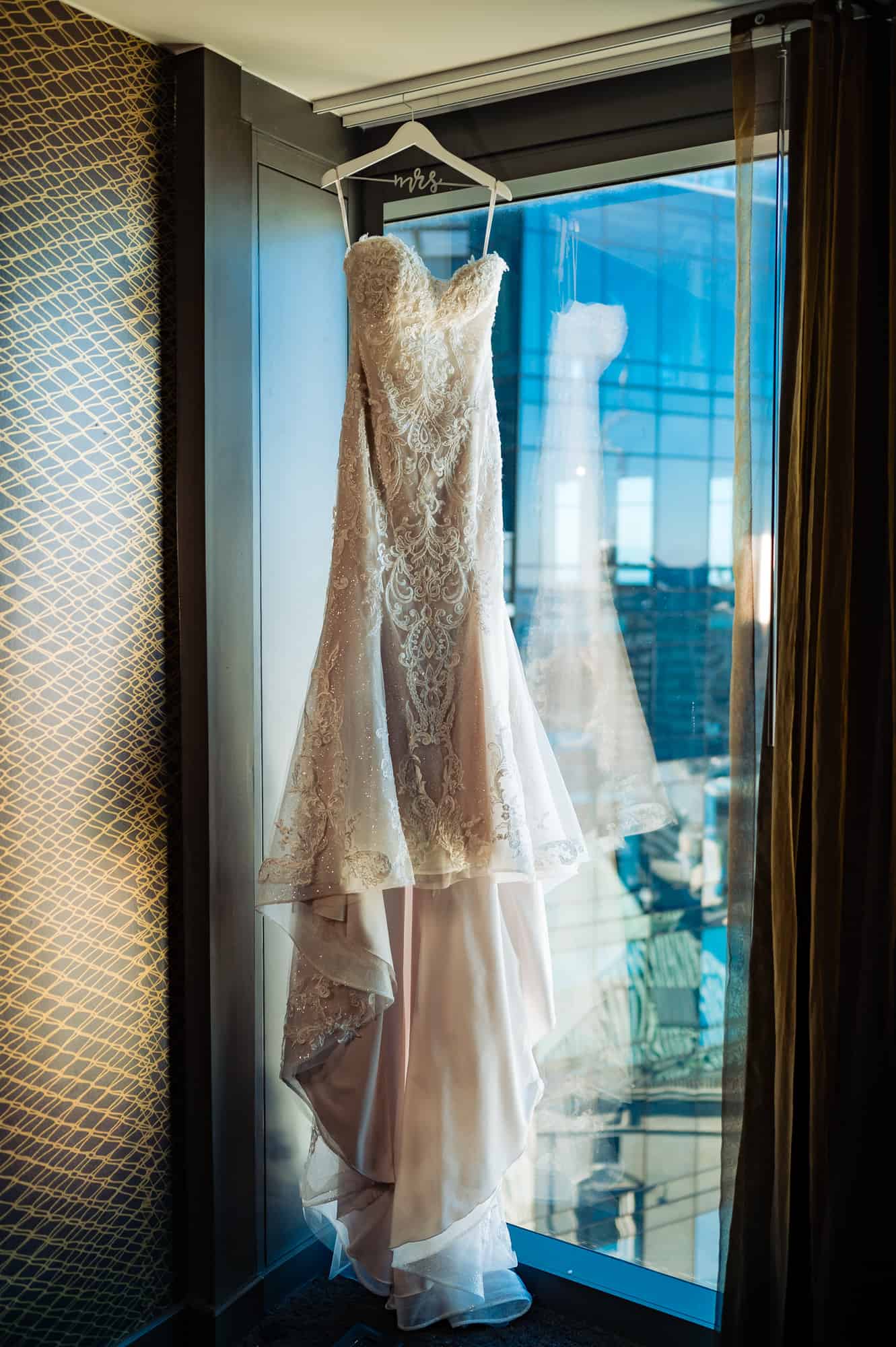 wedding dress hanged near a window in a hotel suite