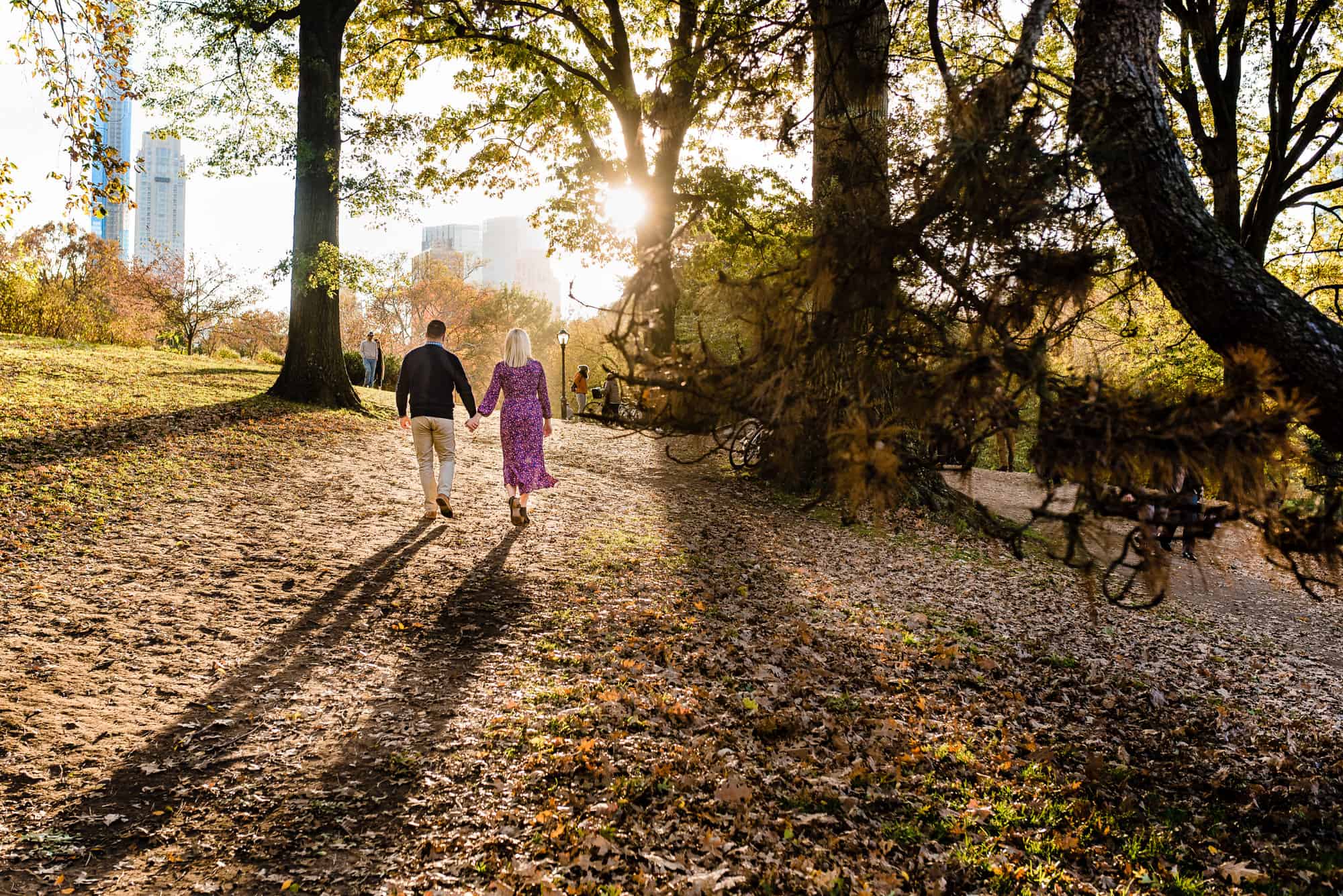 couple walking while holding hands during their central park engagement photoshoot