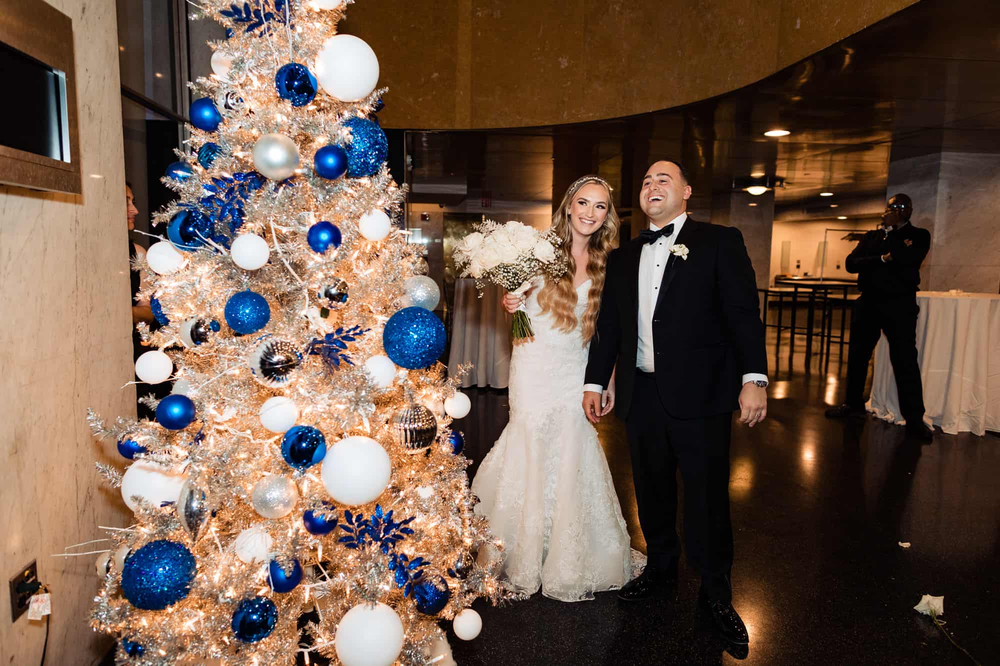 bride and groom posing next to a christmas tree