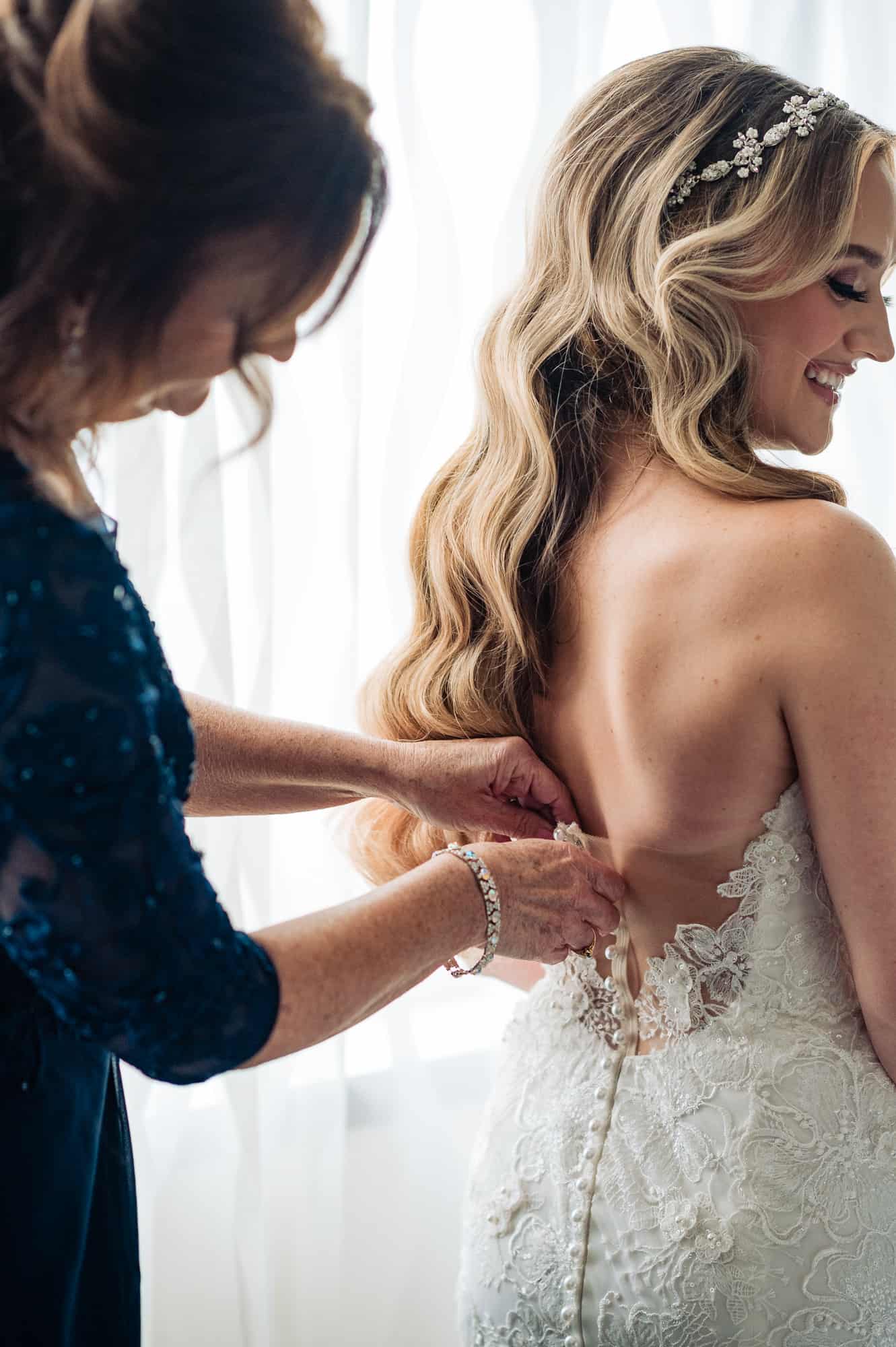 bride's mother helping her wear the dress