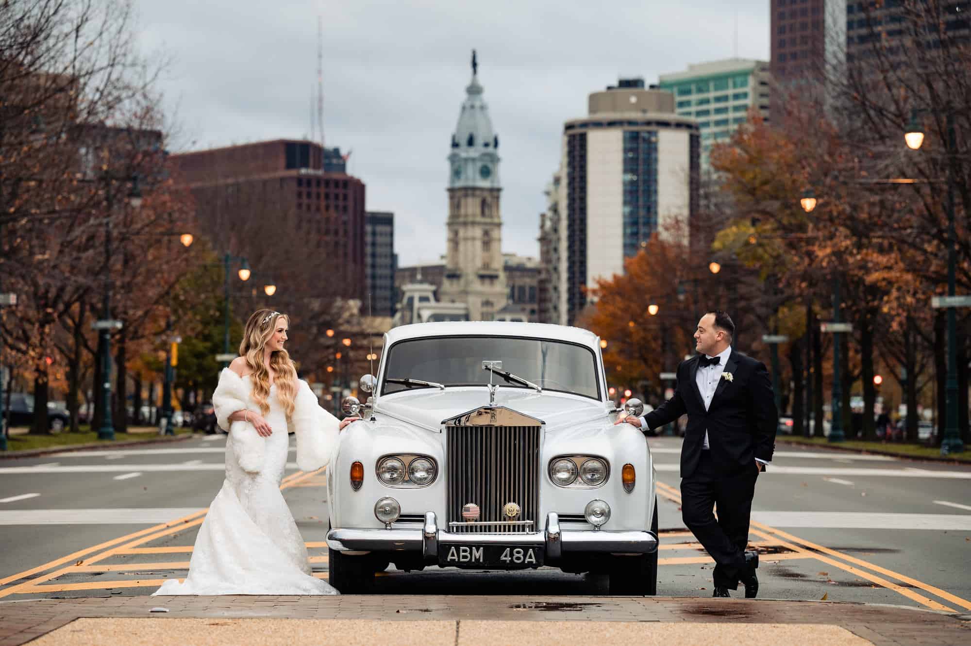 bride and groom posing with their car