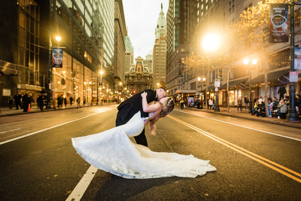 bride and groom kissing in front of the city hall across the street during their Loews Hotel Philadelphia Wedding