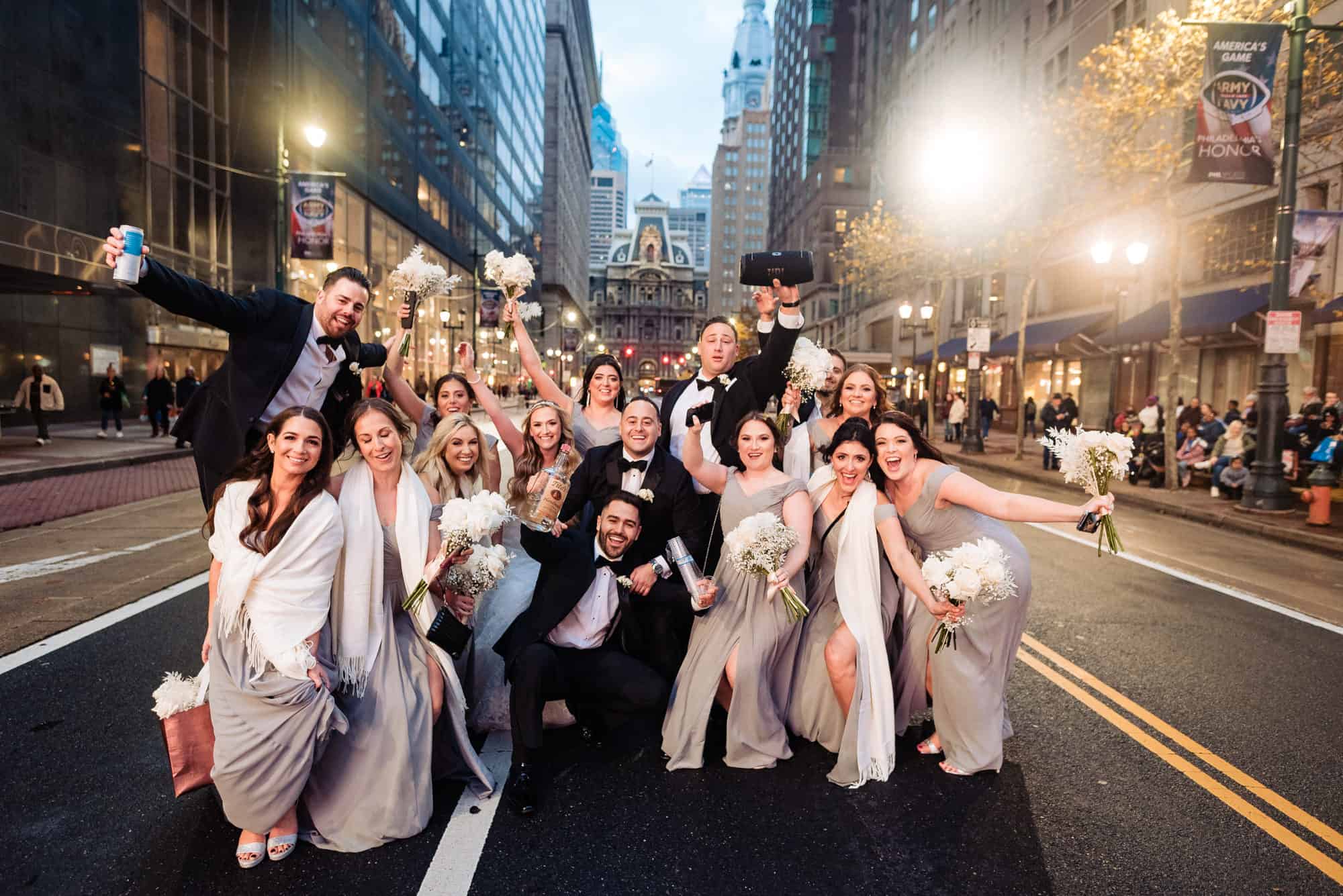 bride and grrom with bridesmaids and groomsmen posing in front of the street