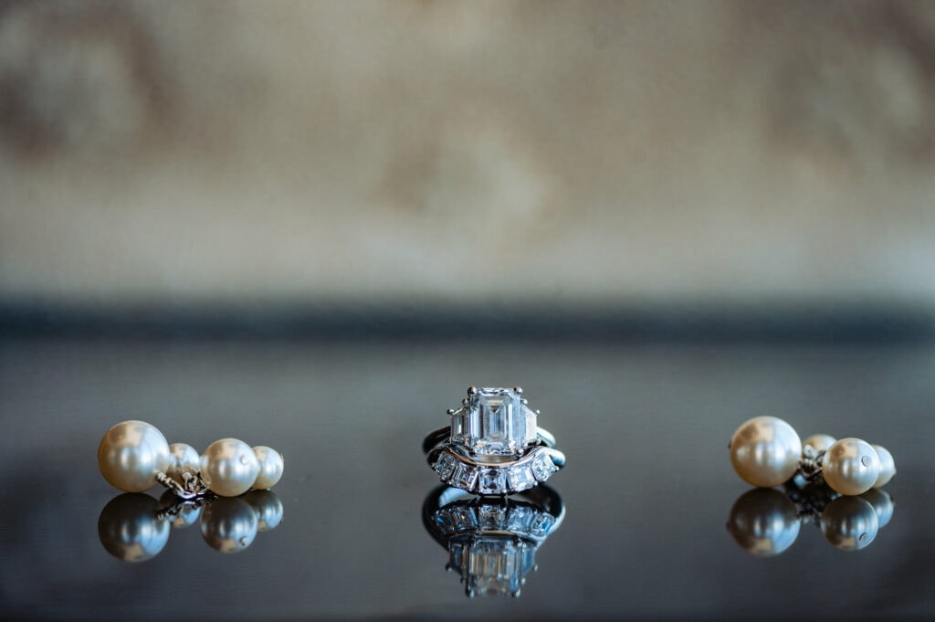 a pair of pearl earrings and a diamond engagement ring