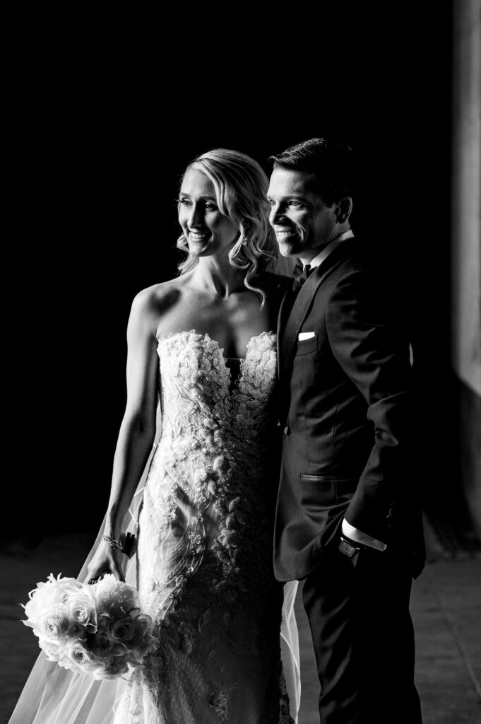black and white shot of bride and groom smiling for the camera