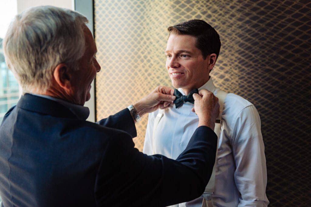 groom's father fixing his son's bow tie