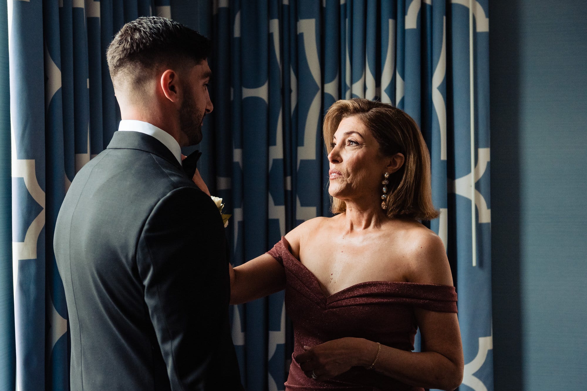 groom gets help from her mother wearing his suit