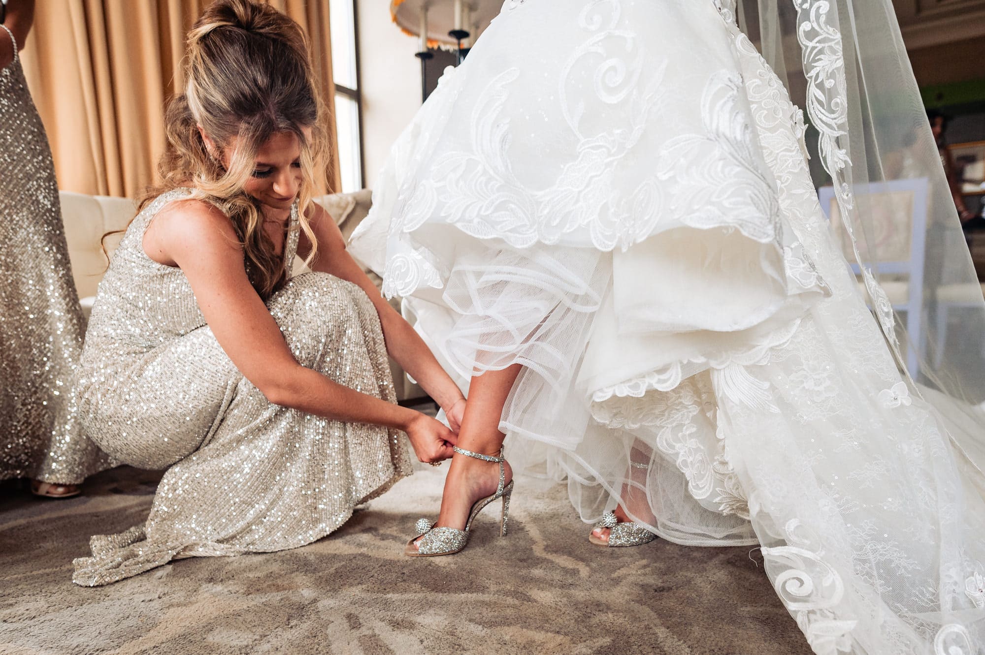 bride's sister helps her put on her sandal