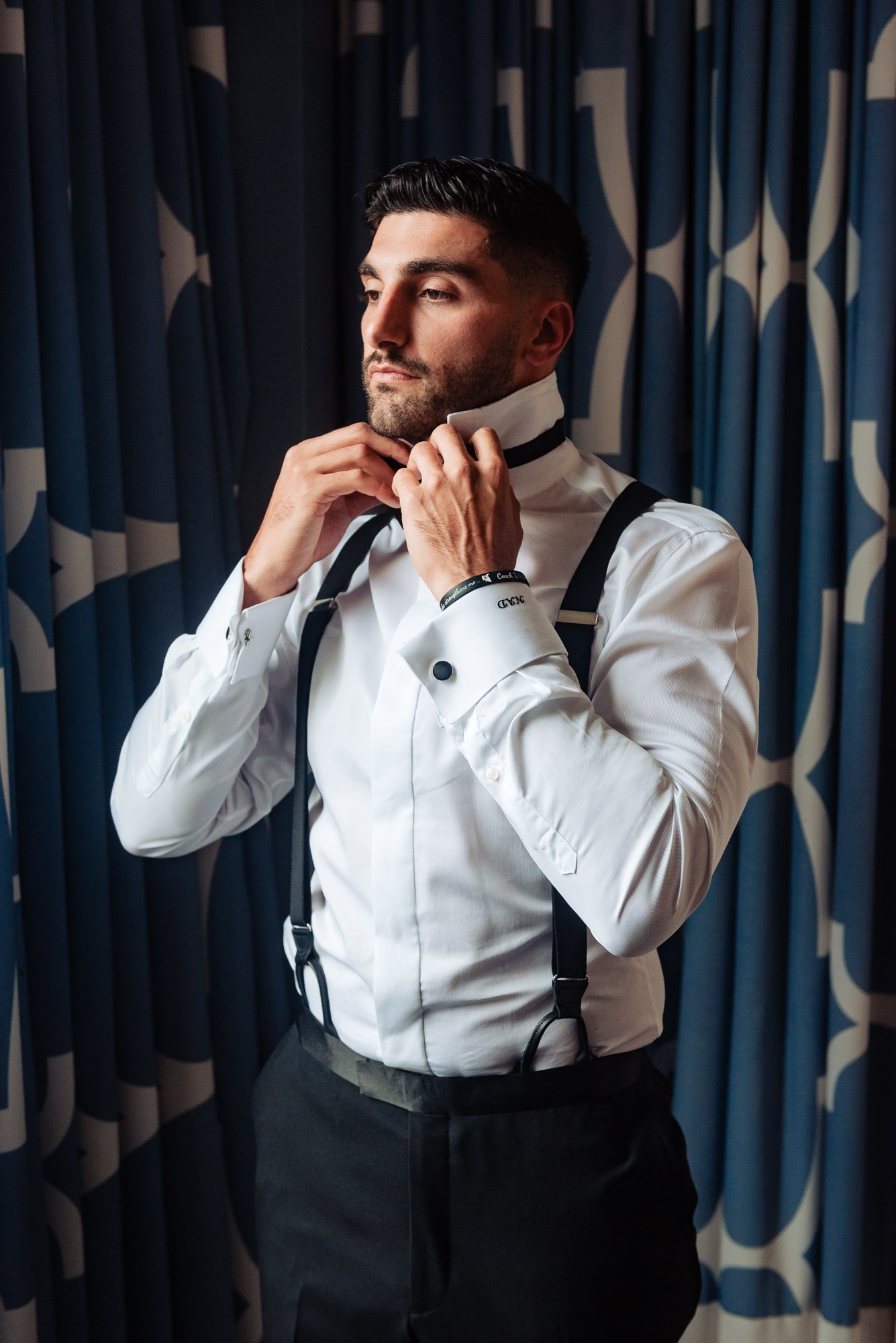 groom is fixing his tie ahead of his wedding at ballroom at the ben