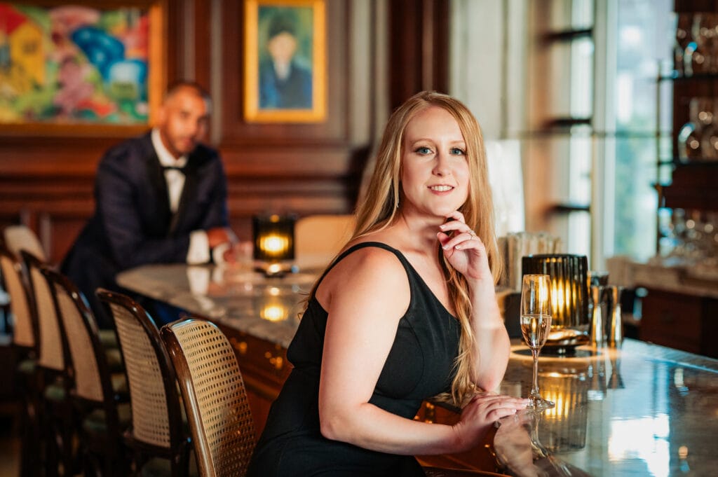 woman in her little black dress sitting in a bar counter smiling at the camera