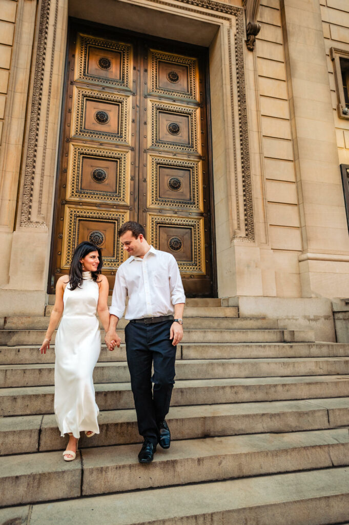 man and woman holding hands as they walk down the stairs