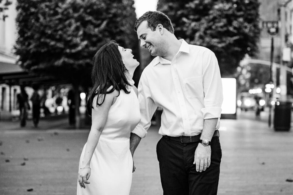 black and white candid shot of man and woman laughing at eachother