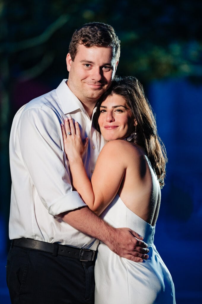 man and woman holding eachother as they pose and smile at the camera for their romantic Manhattan engagement photoshoot