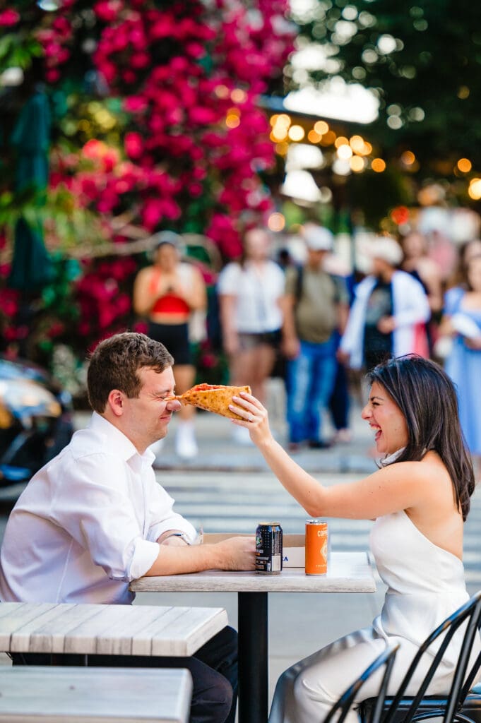 candid shot of woman holding the pizza and putting the sauce on the man's nose