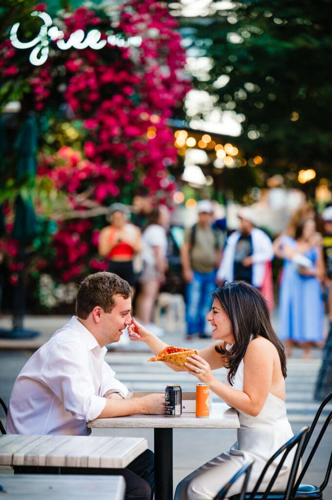 candid shot of woman holding the pizza and wiping the sauce on the man's nose