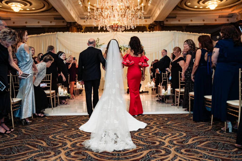back shot of the bride's mother and father walking her on the aisle