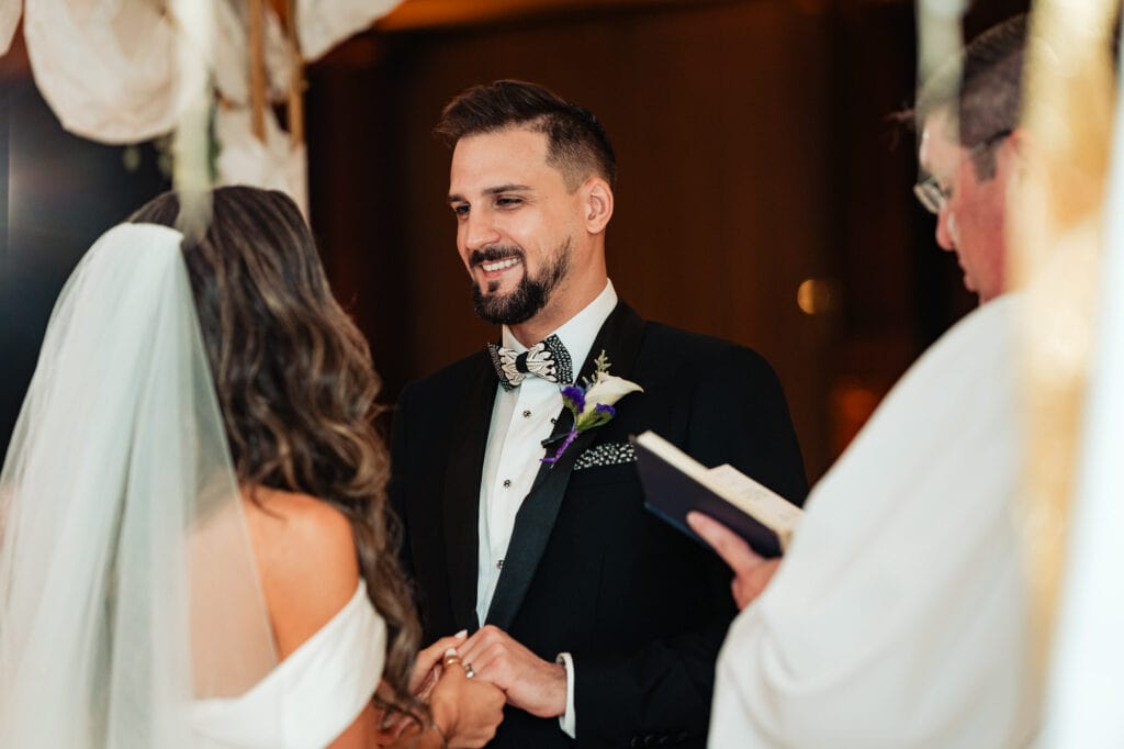 candid shot of the groom at the altar looking at the bride