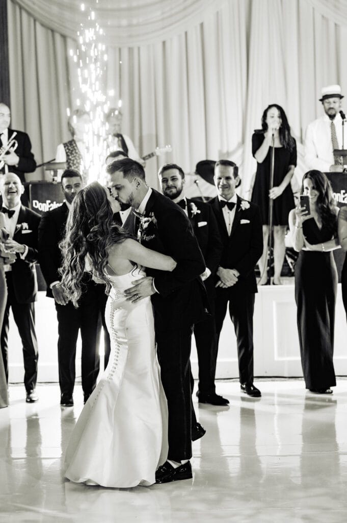 black and white shot of the newlyweds kissing at their wedding reception