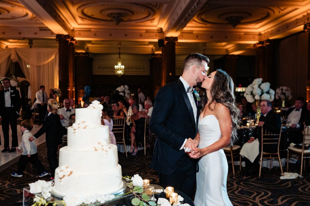 bride and groom kissing in front of their wedding cake