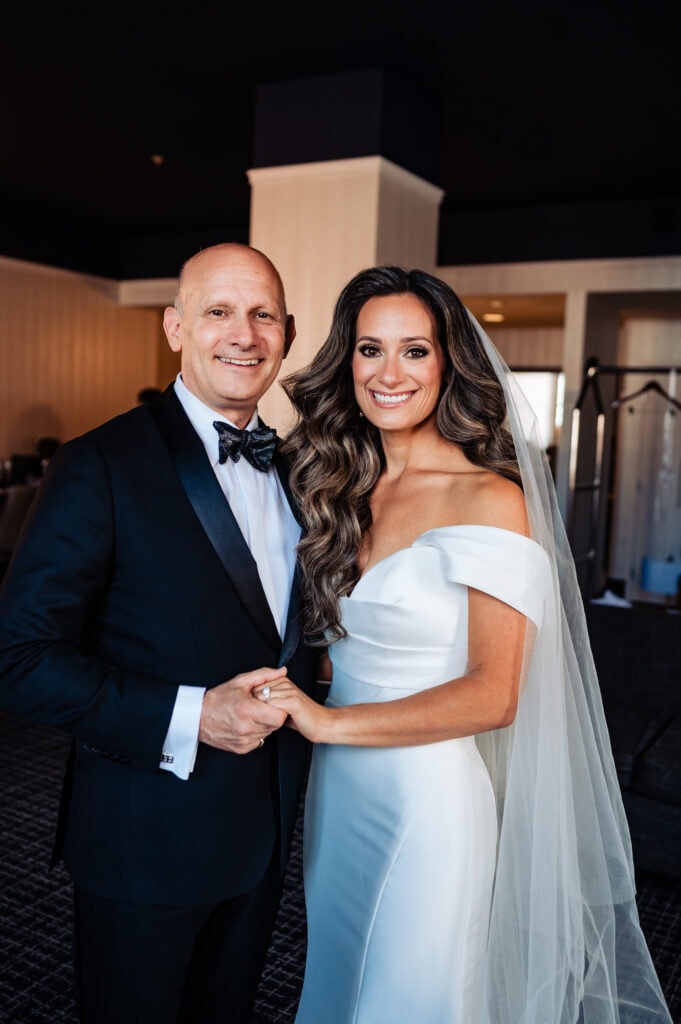 the bride with her father smiling at the camera