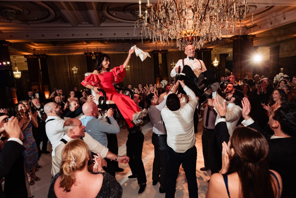 bride's parents being carried while sitting on the chair during the party