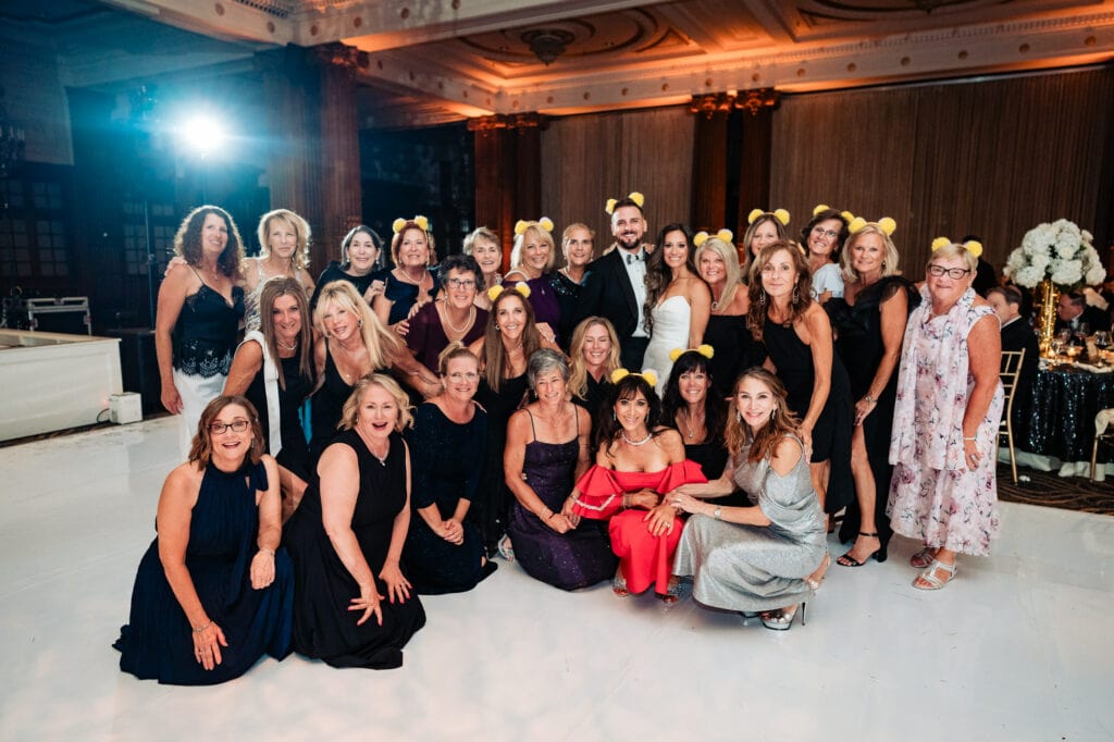 newlyweds group picture with all the female guests while wearing yellow ear headbands