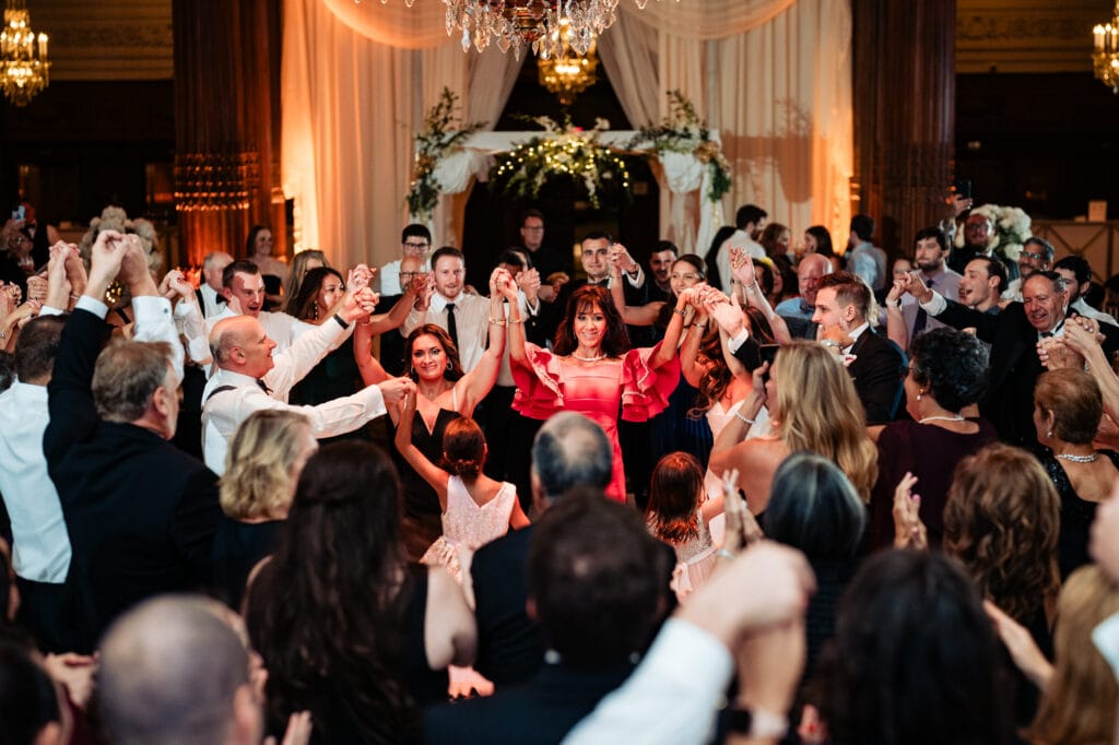 the wedding guests are waving their hands and dancing