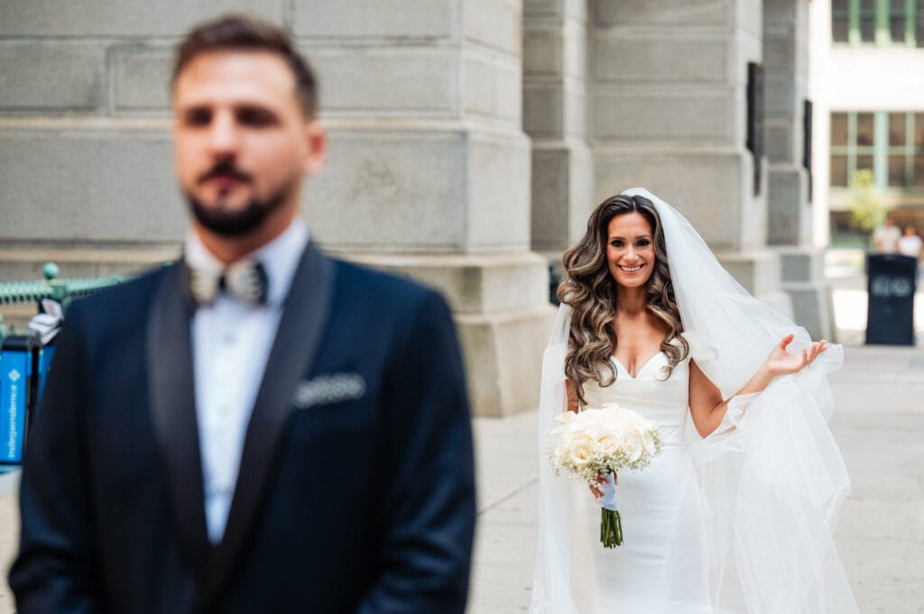 groom is smiling while the bride is standing behind