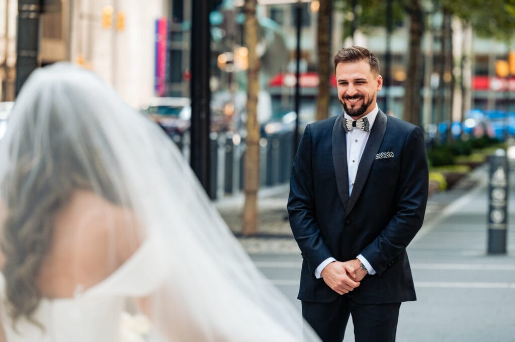 groom is smiling after seeing his bride for the first look