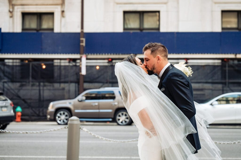 bride and groom kissing on the sidewalk