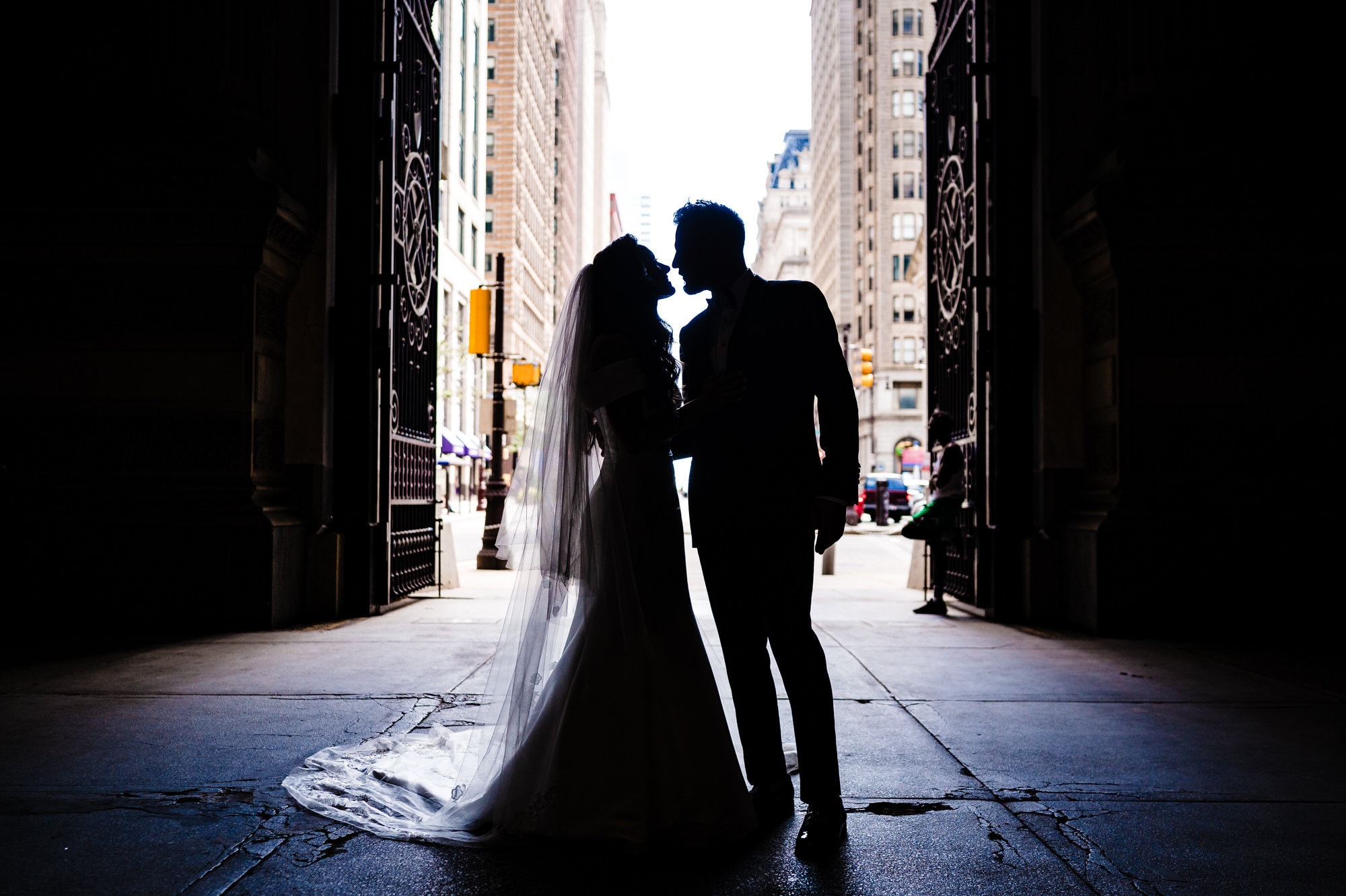bride and groom share a tender kiss in a dark alley against the light background