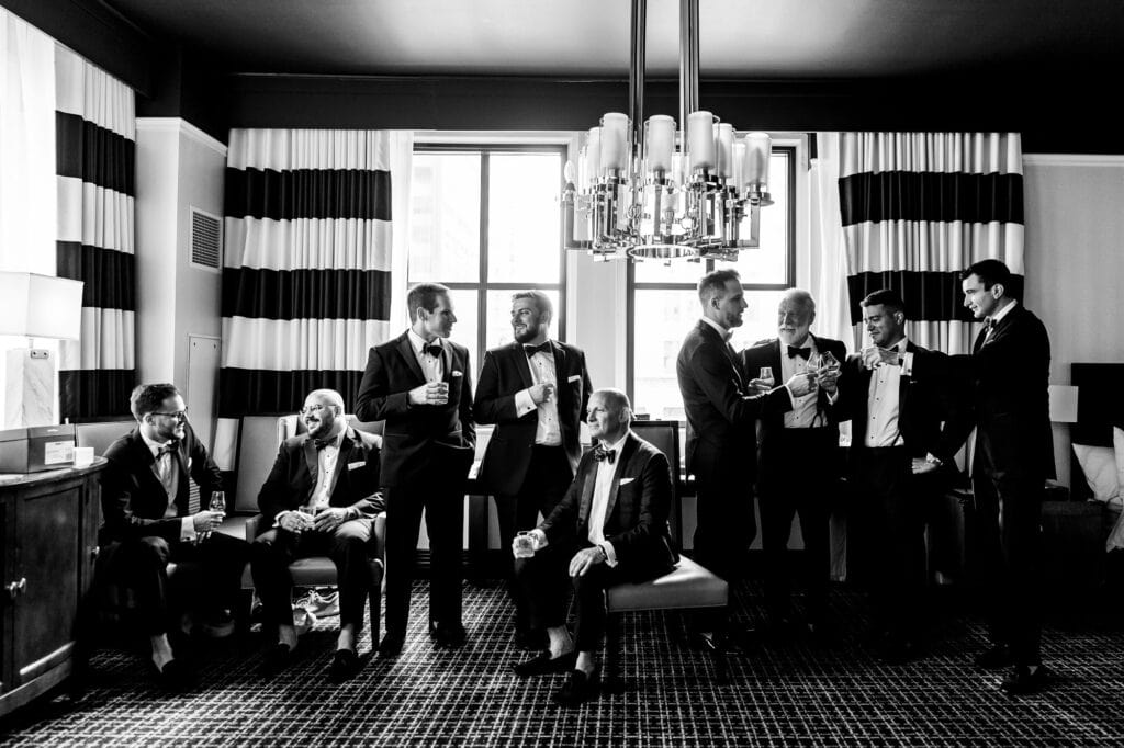 black and white shot of the groom having a drink with the groomsmen