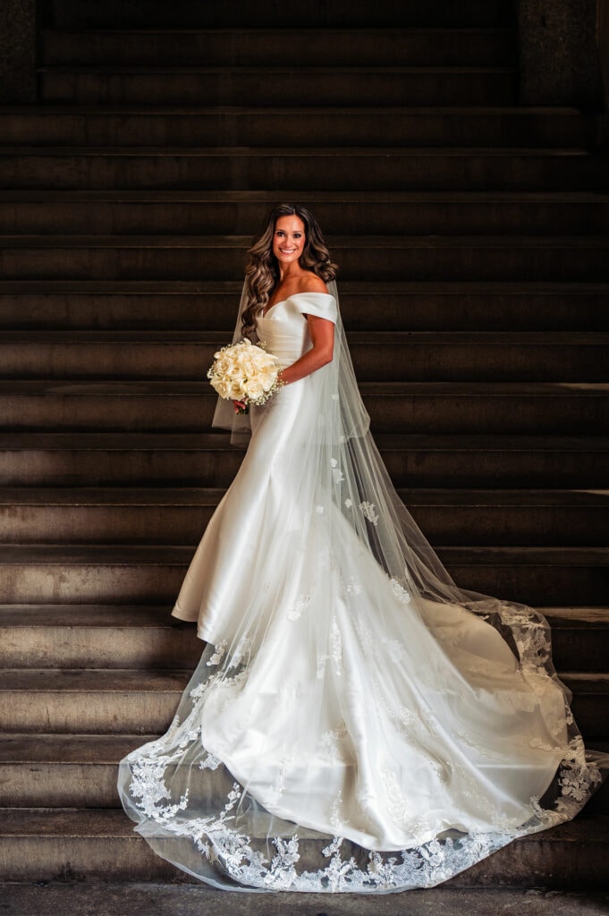 bride on the stairs holding her bouquet posing for the camera