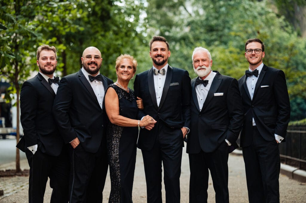 groom poses for the camera along with his family