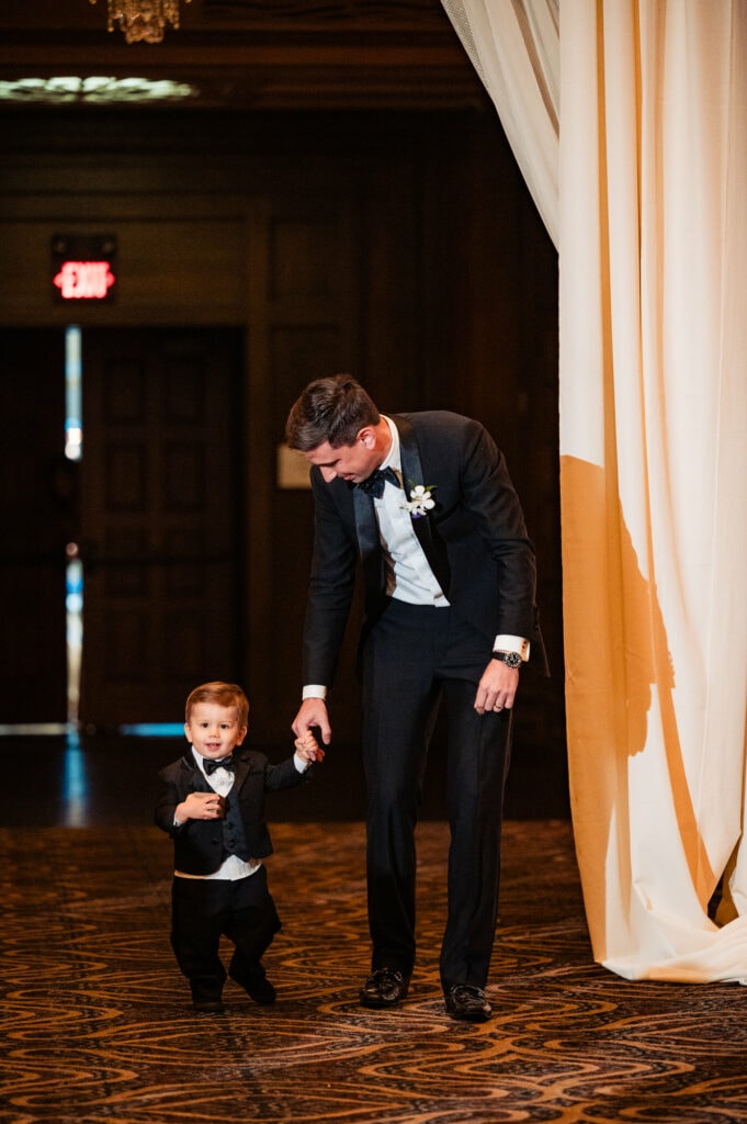 a toddler is walking down the aisle with his father
