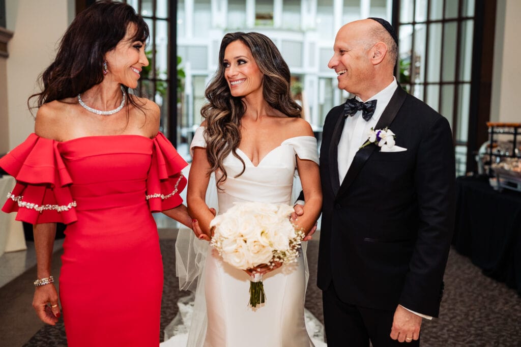 bride is walking down the aisle with her parents
