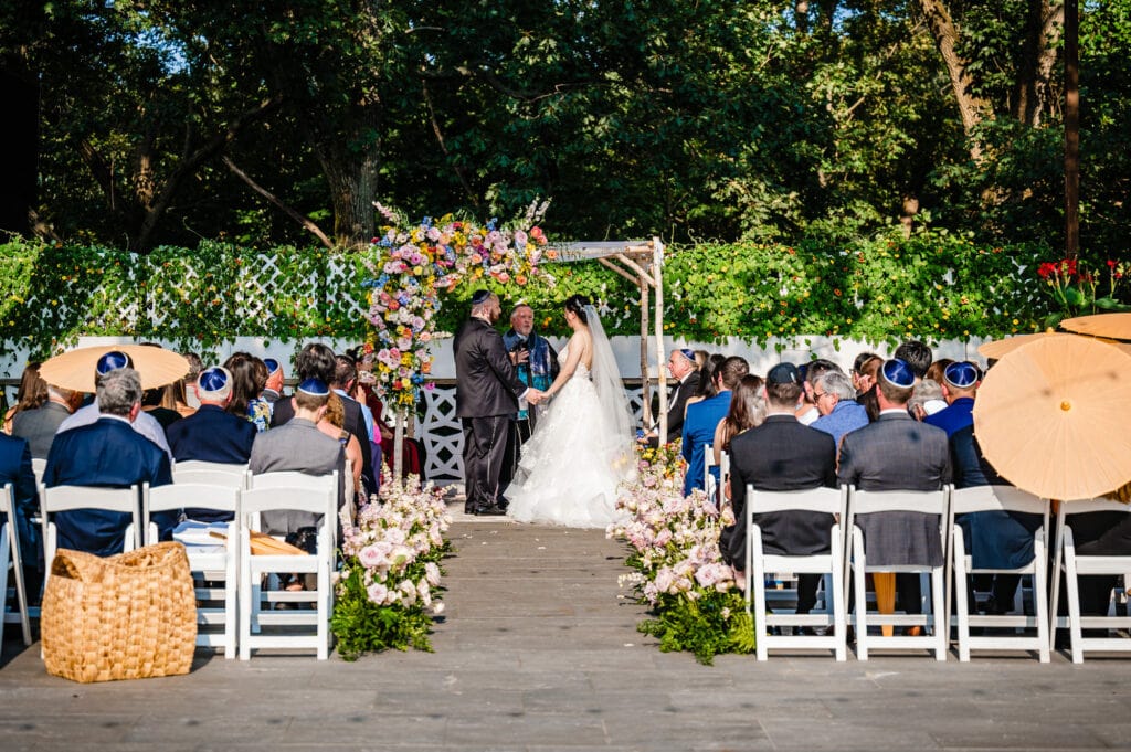 the newlyweds recite their wedding vows under the chuppa in an outdoor Jewish wedding ceremony